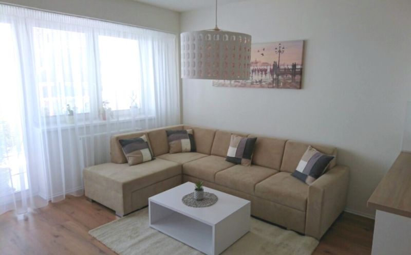 Living room in a 3-room apartment with a corner sofa and a floor with a wooden decor.