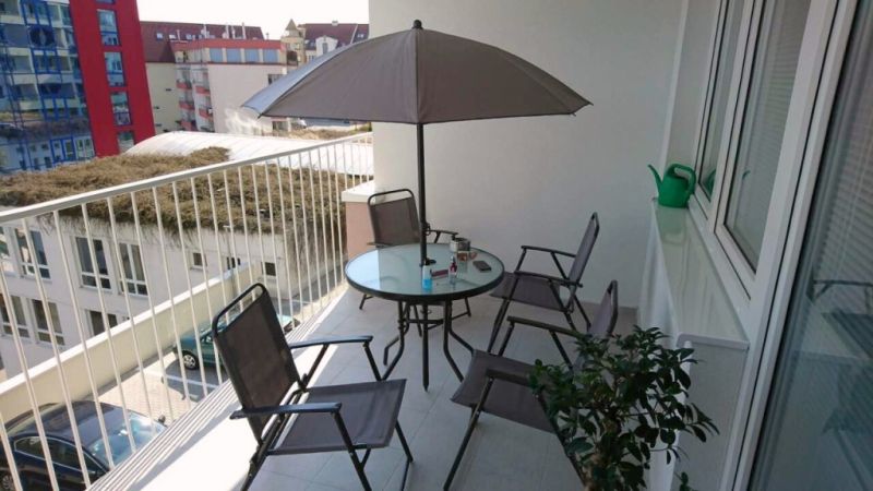 Balcony of a 3-room apartment Above the Beach in Banská Bystrica with seating and a sunshade.