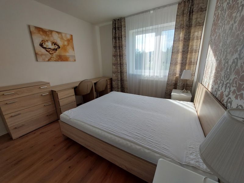 A bedroom with a large bed, a floor with a wooden decor, and a decorative painting in a 3-room apartment.