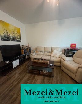Living room of a two-room apartment with a wood-patterned floor and comfortable seating.