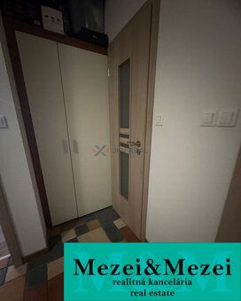 A hallway in a 2-room apartment with a wooden decor floor and a built-in wardrobe.