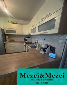 A kitchen in a 2-room apartment with a wooden decor floor and light furniture.