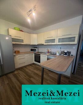 A kitchen with light cabinets and a wood-patterned floor in a 2-room apartment.