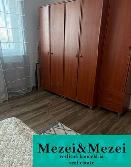 A room in a 2-room apartment with wardrobes and a floor with a wooden decor.
