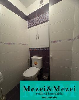 A bathroom in a 2-room apartment with tiles in shades of white and purple.