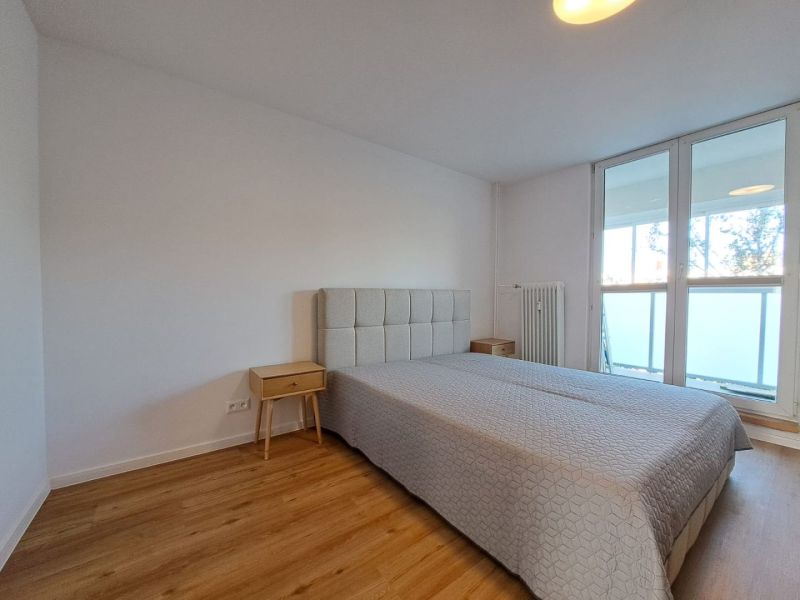 A bedroom in a 2-room apartment with a bed and a wooden decor floor.
