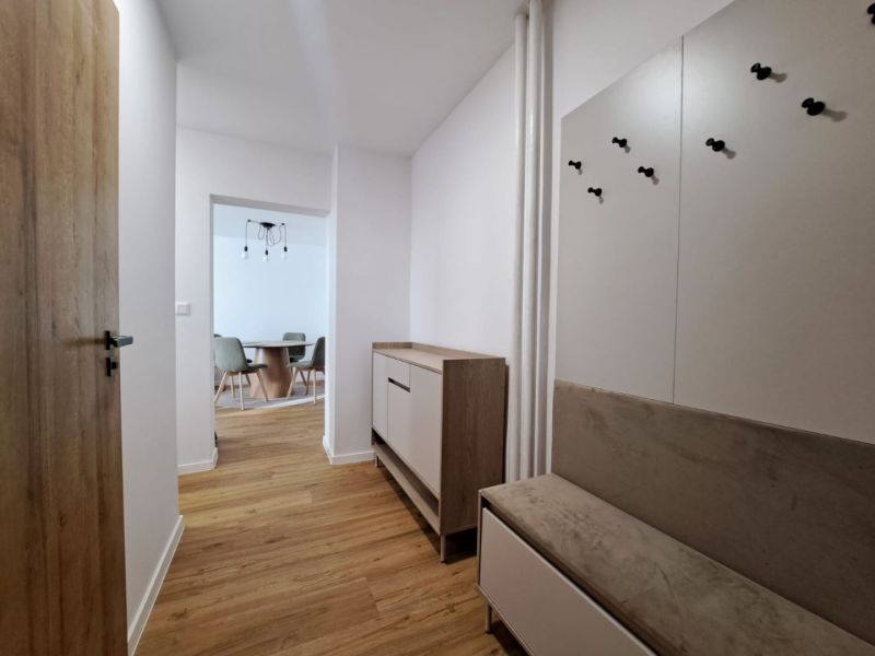 A hallway in a 2-room apartment with a wooden decor floor, hallway furniture, and a dining area.