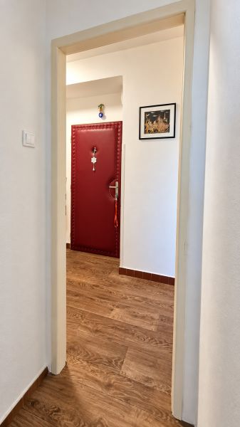 A hallway with red doors and a wooden decor floor in a 3-room apartment.