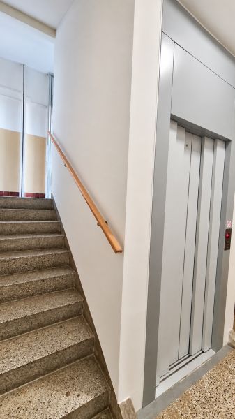 Staircase with railing and elevator in a building near a 3-room apartment.