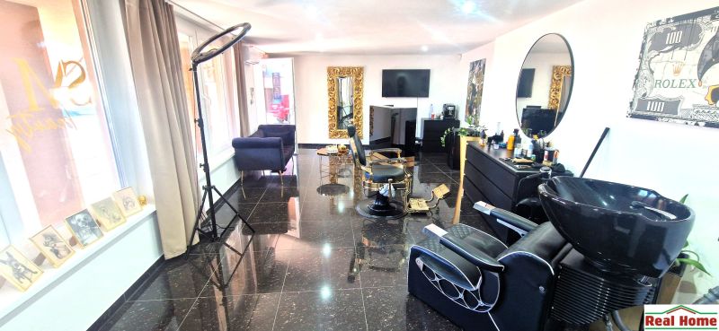 Hair salon with black granite flooring, large mirrors, and comfortable chairs.