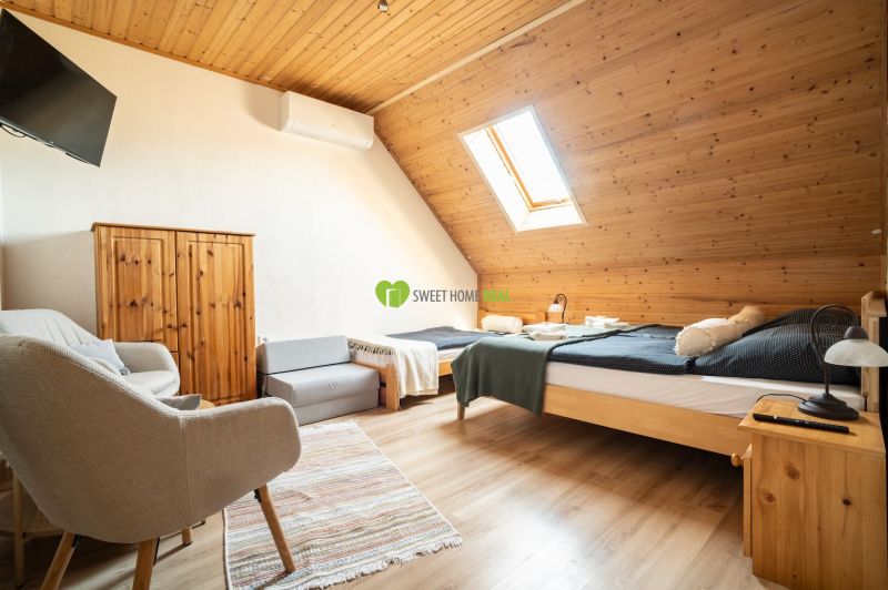 Attic room with a bed, chair, skylight, and wooden decor flooring.