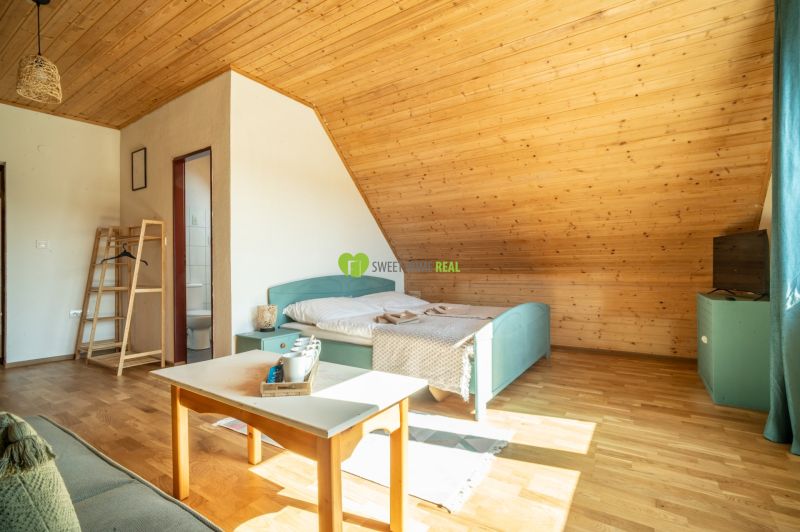 Attic room with a bed, table, and wooden decor flooring in a hotel.