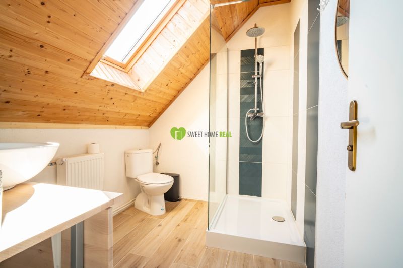 Attic bathroom with a sink, shower, and floor with wood decor.