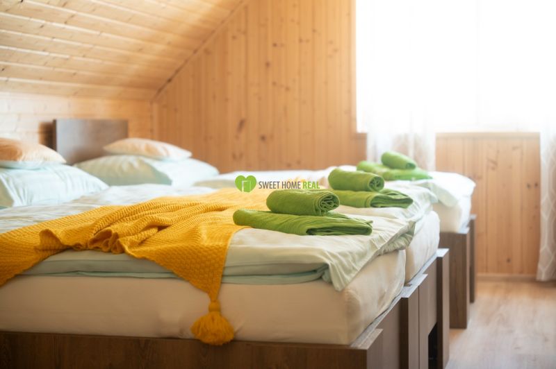 A room with two beds, a yellow blanket, and wooden paneling in hotels and guesthouses.