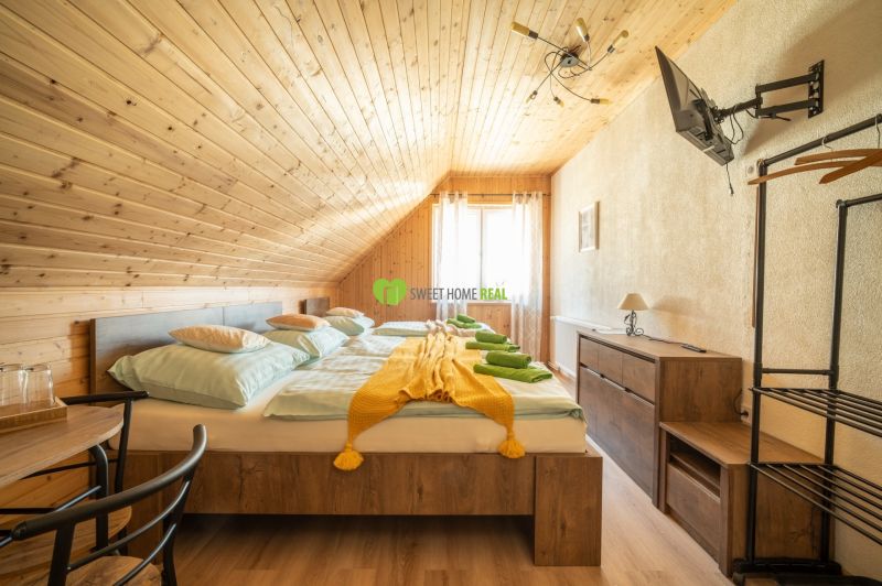 A room with wooden paneling, a double bed, a TV, and a floor with a wooden decor. Hotels and guesthouses.