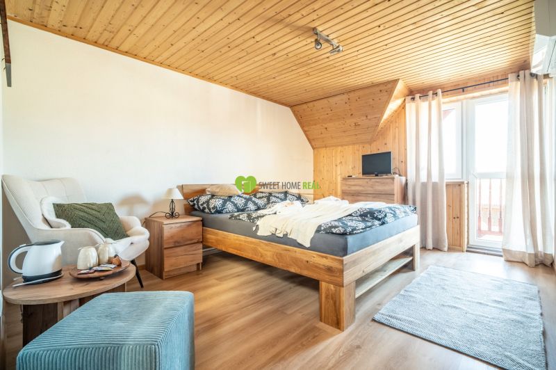A hotel room with a bed, chair, carpet, and wooden decor flooring.
