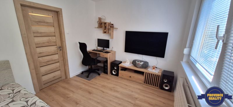 A workspace with a computer and television, wooden decor flooring in a 3-room apartment.