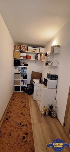 A compact room with shelves, a wardrobe, and a floor with a wooden decor in a 3-room apartment.