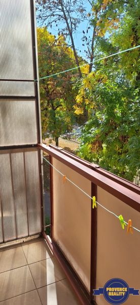 Balcony of a 3-room apartment in Komárno with a view of green trees.