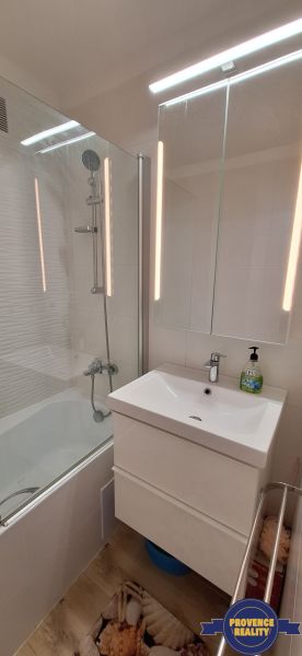 A bathroom in a 3-room apartment with a bathtub, a mirrored cabinet, and a floor with a wooden decor.
