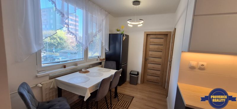 Dining area with a window, dark refrigerator, curtains, and a table in a 3-room apartment.