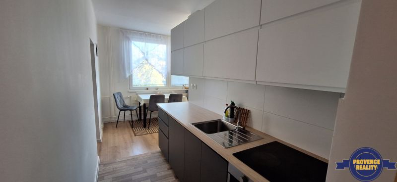 A kitchen in a 3-room apartment, with a wooden decor floor and a dining area.