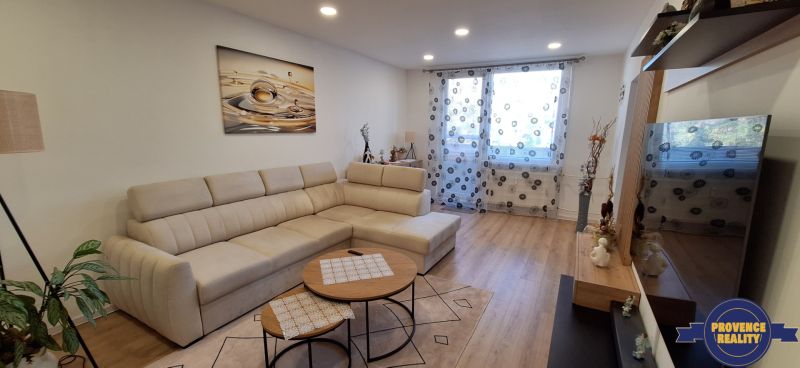 Bright living room with a corner sofa and wooden decor flooring in a 3-room apartment.
