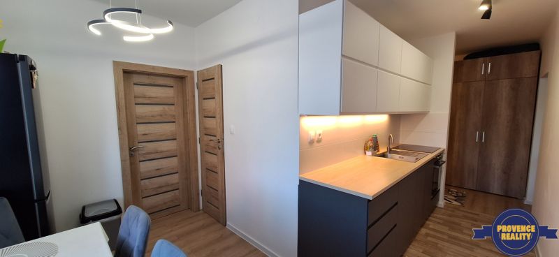 A kitchen in a 3-room apartment with a wooden decor floor and modern lighting.