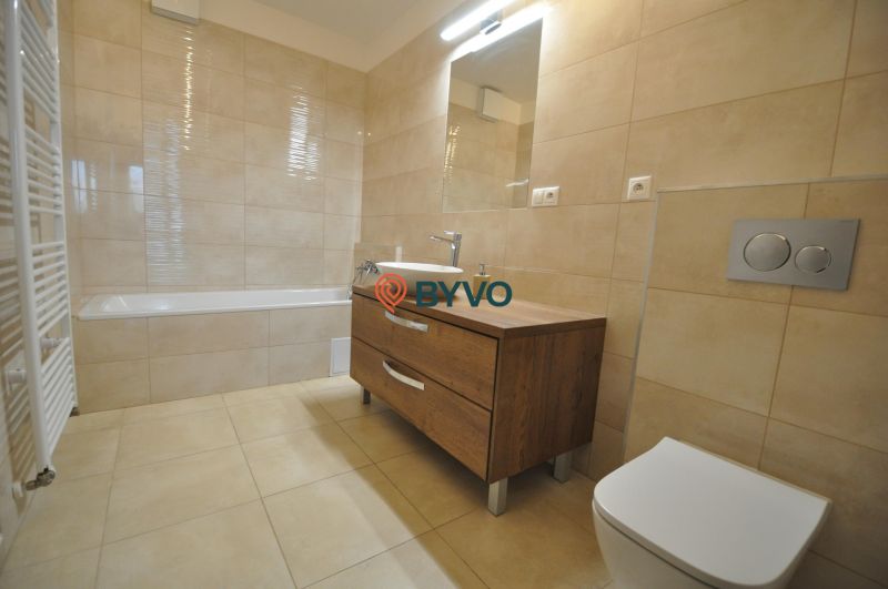 A bathroom in a 3-room apartment with a bathtub, a sink, and a cabinet with a wooden decor.