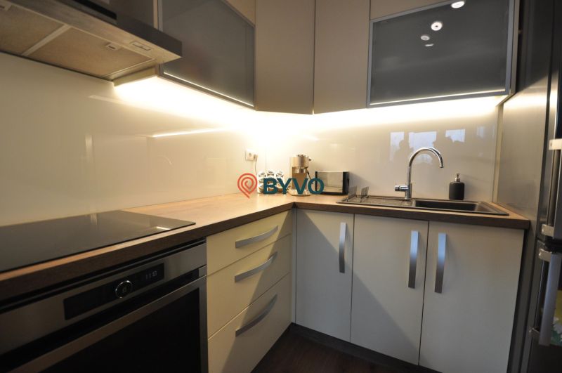 A kitchen in a 3-room apartment with a linear kitchen unit and a floor with a wood decor.