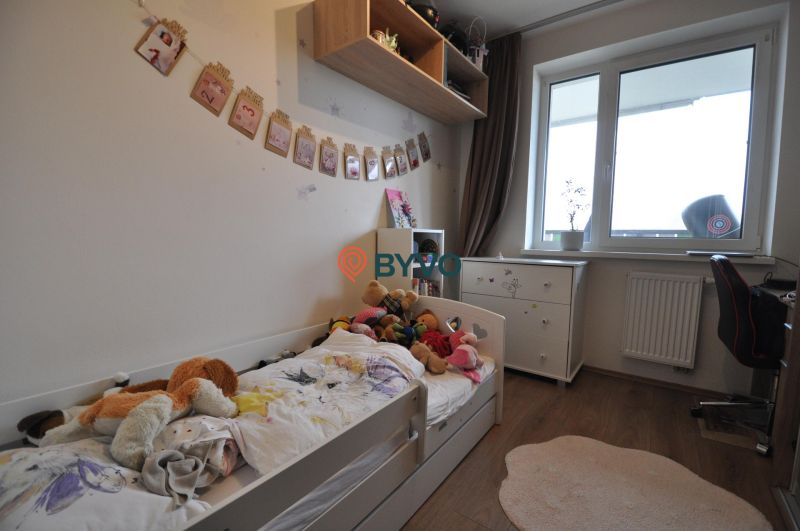 Children's room in a three-room apartment with a wooden decor floor and a window.