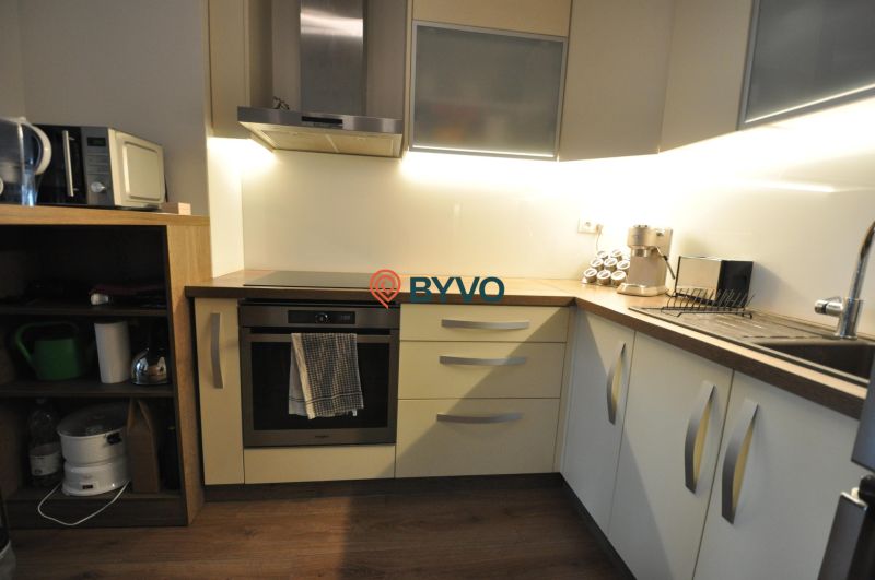 A kitchen in a 3-room apartment with a wooden decor floor and a modern kitchen unit.
