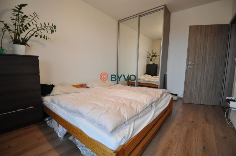 A bedroom with a bed, a wardrobe with a mirror, and a floor with a wooden decor in a 3-room apartment.