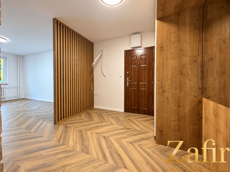 Interior of a 3-room apartment with a wooden decor floor and a wooden wall.