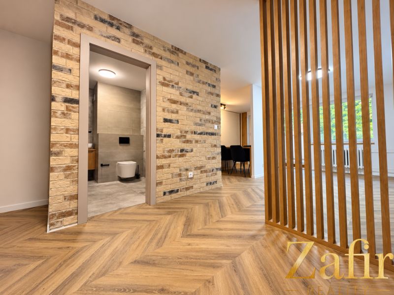 Interior of a 3-room apartment with a wooden decor floor and a brick wall.