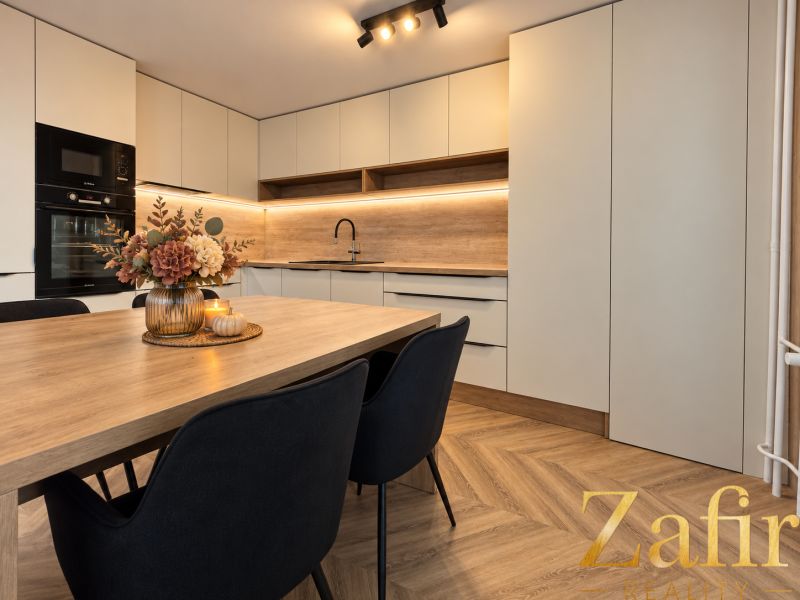 A kitchen in a 3-room apartment with a wooden decor floor and modern furnishings.