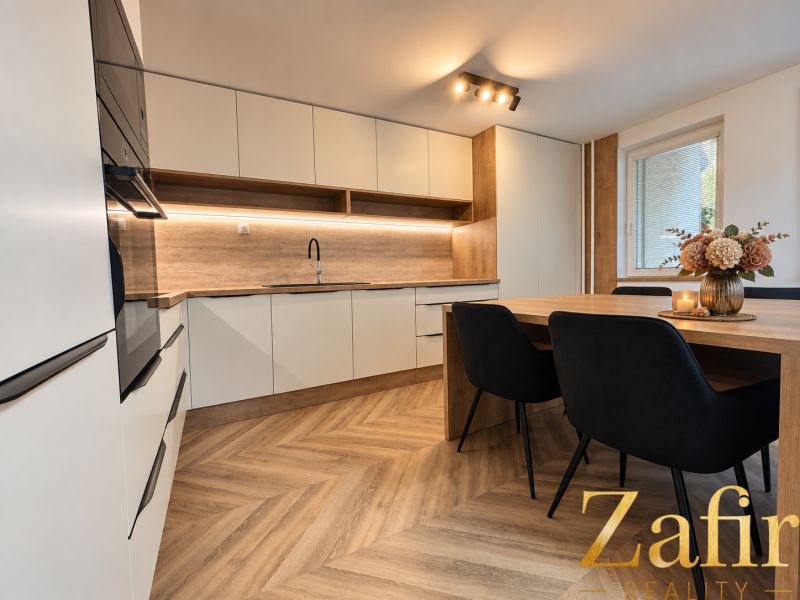 A kitchen in a three-room apartment with a wooden decor floor and a dining table.