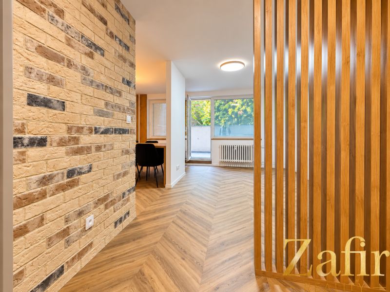 Interior of a 3-room apartment with a brick wall and a wooden decor floor.