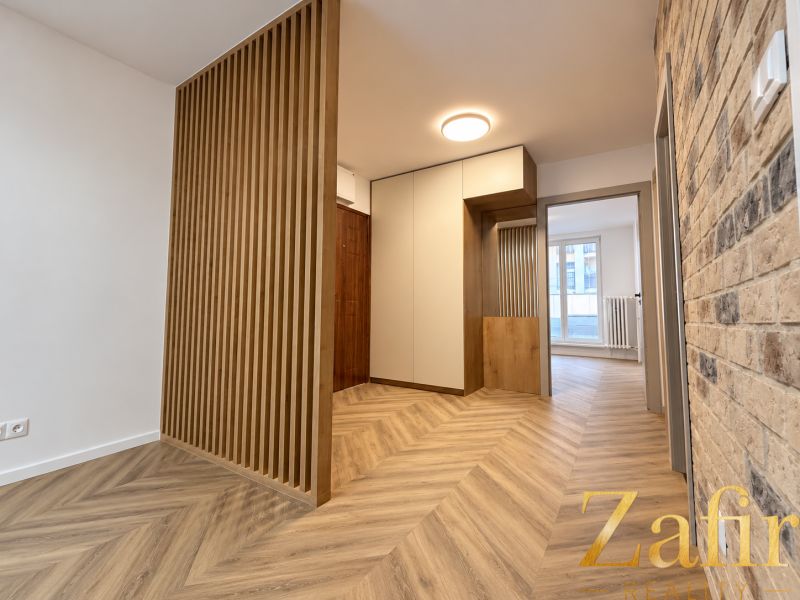 Interior of a 3-room apartment with a brick wall and a floor with a wooden decor.