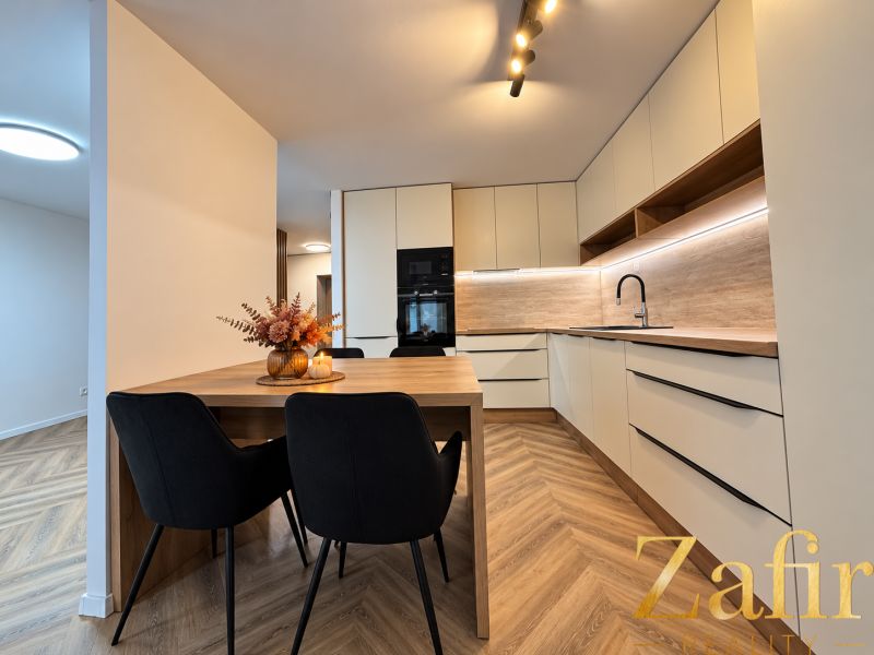 A kitchen in a 3-room apartment with pleasant lighting and a wooden decor floor.