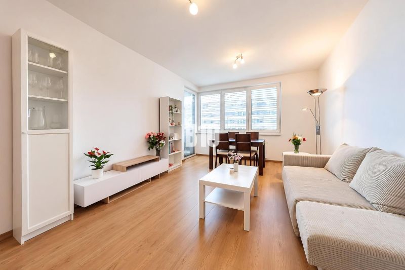 Living room in a two-room apartment with a wooden decor floor and light furniture.