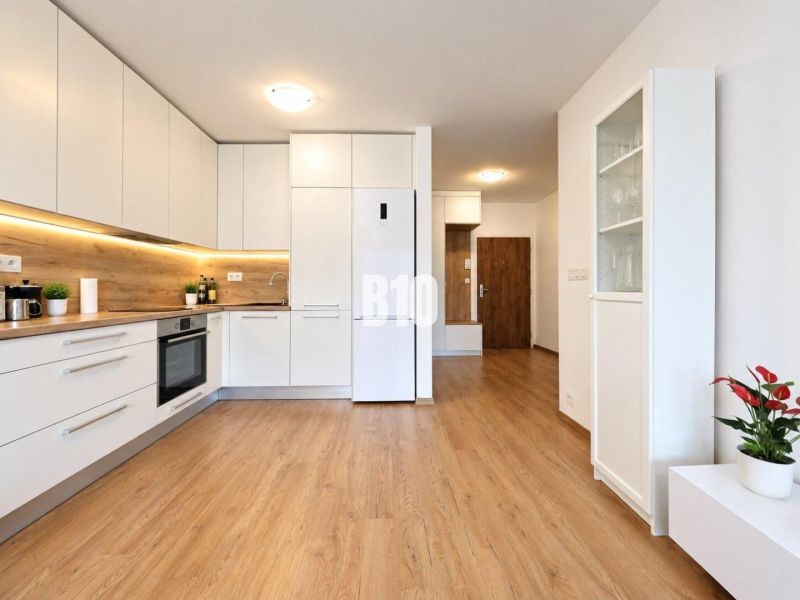 A kitchen in a 2-room apartment with a white kitchen unit and a floor with a wood decor.
