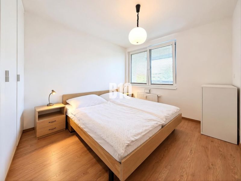 A bedroom in a 2-room apartment with a bed, a nightstand, and a floor with a wooden decor.