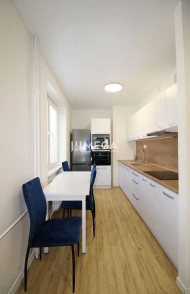 A kitchen with white cabinets and a wood-patterned floor in a 2-room apartment.