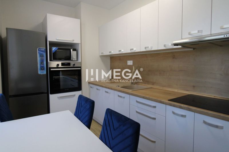 A modern kitchen with white furniture and a wooden decor floor in a two-room apartment.