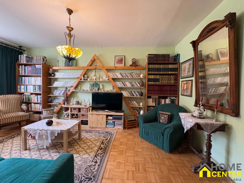 Living room in a 3-room apartment with a wooden decor floor and a rich library.