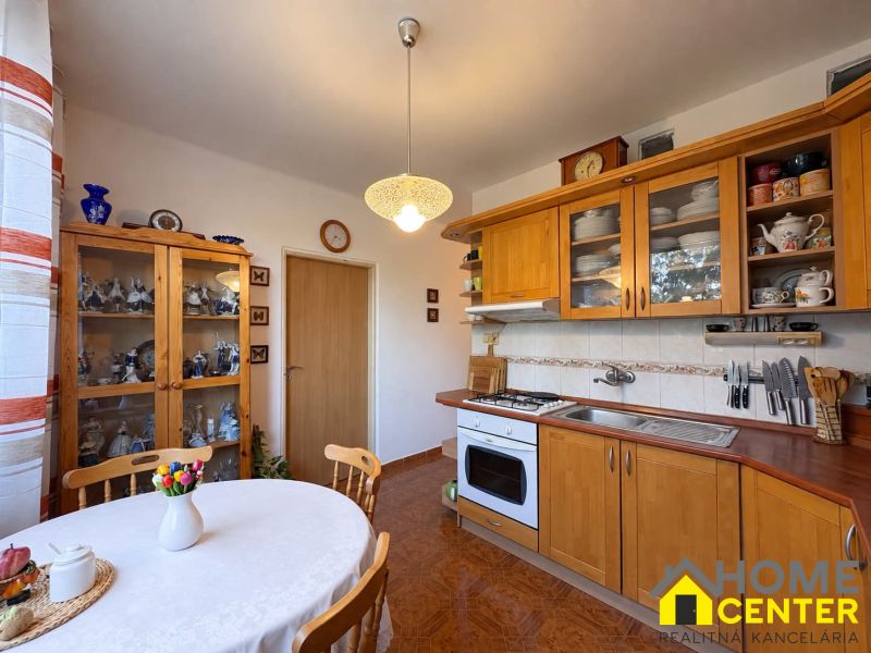 A kitchen in a 3-room apartment with wooden decorations, plates, and a vase with flowers.