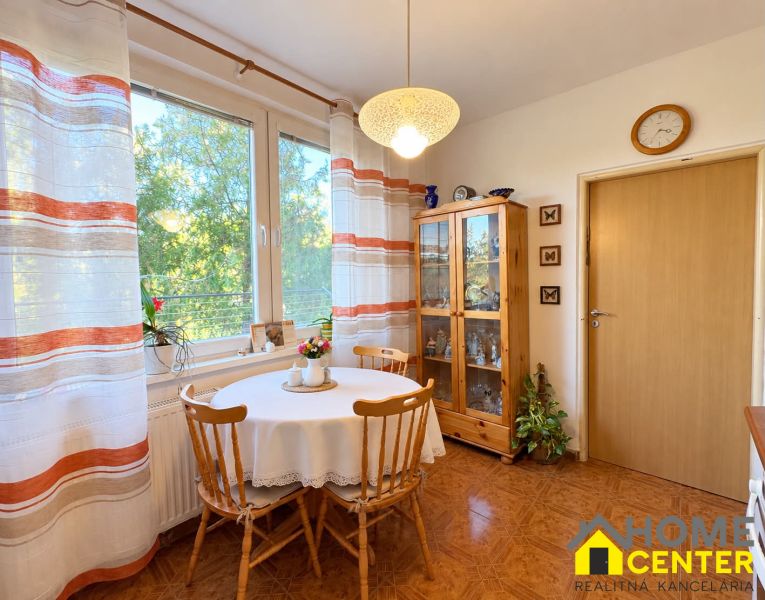 A clear kitchen in a 3-room apartment with a wooden decor floor and a dining table.