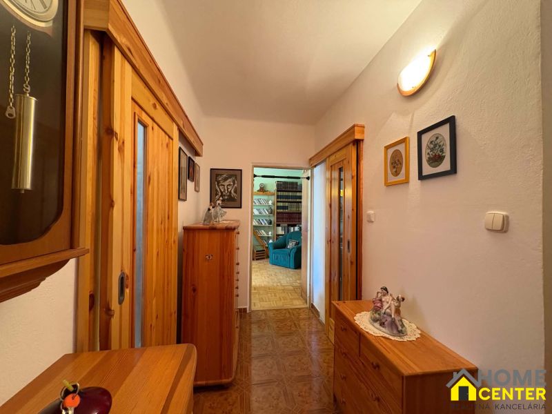 A hallway in a 3-room apartment with a wooden decor floor and wooden furniture.