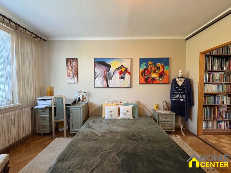 A bedroom in a 3-room apartment with a wooden decor floor and art paintings on the wall.